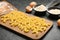 Board with homemade pasta and flour on dark table