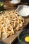 Board with homemade pasta, flour and ingredients on dark table