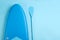 Board and paddle for standup paddleboarding (SUP) on light blue background, flat lay. Space for text