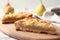 Board with pieces of delicious  pear tart on table, closeup