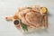 Board with raw spiced turkey and ingredients on light background