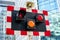 Board with red and white squares, orange traffic lights and speaker, used for signal during roadworks, blurred modern