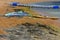 Board with a sail for windsurfing lessons is on a sandy beach next to the sea in the background of yellow sand.