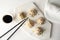 Board with tasty baozi dumplings, chopsticks and bowl of soy sauce on white wooden table