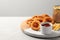 Board with tasty ketchup, fries and onion rings on light grey table, space for text
