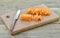 Board with thin slices, small stick carrots and knife on wooden table, closeup