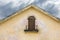 boarded up balcony on weathered plaster wall of gable with peeling paint