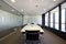 Boardroom with long wooden table with black swivel chairs and wall with windows