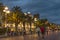 Boardwalk and street in Nice, France, at twilight with colorful light effects and walking tourists