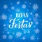 Boas Festas calligraphy isolated on blue background with bokeh and snowflakes. Happy Holidays lettering in Portuguese. Christmas