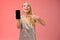 Boastful proud charming elegant blond woman in stylish evening dress show smartphone display proudly pointing mobile