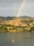 Boat in the Akaroa harbor in New Zealand, with a vibrant rainbow stretching across the sky