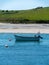 Boat is anchored near the picturesque shores of southern Ireland. Seaside landscape. Green hilly coast, boat on seashore