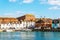 Boat anchored in a small harbor, in the background stone buildings and promenade, seaside