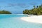 Boat anchoring on small island in turquoise clear water, deep blue sky, white sand, Pacific Island