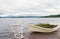 Boat as flower pot and iron fisherman on pier on lake