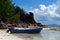 Boat at the beach on Curieuse Island, Seychelles, with lava stone rocks and lush vegetation