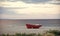 Boat on the beach. Fishermens boat at seacoast, on sand on cloudy day with sea on background. Fishing boat on beach in