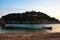 Boat on the beach with green island in the background. Fishing boat parked on the sandy beach.