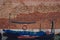 Boat in canal by an old red brown brick wall, in Venice, Italy