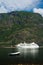 Boat and cruise ship in sea on mountain landscape in Flam, Norway. Sea vessels in harbor with green mountains