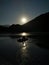 A boat with fishermen on the river on a moonlit night.  Moon, river and mountains at night.