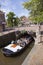 boat full of tourists passes colorful flowers on bridge in centre of old historic town leeuwarden in the netherlands