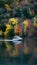 Boat glides through a tapestry of fall colors on the lake