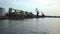 Boat going by sea, approaching wharf with immense storehouses and cranes at port