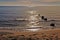 Boat on horizon, with rocks, sandy beach and suns rays reflected on to mediterranean sea, palma, mallorca, spain