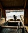 Boat house with a small boat with motor and oars, seen from the inside, looking out at the ocean.