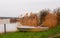 A boat on a lake in Pavlovka fishing resort not far from Odessa, Ukraine. Yellow dry reeds, blooming spring tree, calm