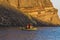 A boat moored on the edge of the island of Thirasia, Santorini as the sun sets