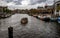 Boat navigating the Amsterdam waterways with parking boats around