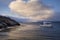 Boat near a desertic islandÂ´s shore with sea birds and a cloud with sunlight in Ushuaia, Argentina