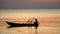 Boat on open sea sunset horizon. The boatman in the Vietnamese hat in the small boat. The man fishes at sunset. Close up