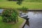 Boat parked on the canal near the beautiful hydrangea bush.