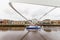 Boat passing under tilted Millennium Bridge in Newcastle, UK