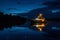 A boat peacefully floats on top of a dark lake under the night sky, Night-time view of a patrol boat with its lights twinkling on