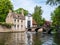 Boat with people, bridge over canal and entrance gate to Begijnhof, Beguinage, in Bruges, Belgium