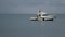 Boat sailed up to ship in harbor. Background of gray overcast sky. Small boat