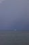 Boat sailing in the upcomming storm. Sailboat in bad weather sail at opened sea. Sailing yacht under heavy cloud sky.