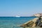 The boat sails far into the sea on the background of rocks. Mediterranean landscape. View of the blue sea. Yacht sailing