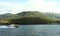 Boat sails on the sea on the left side. There mountain in background. Sea is blue. Motorboat. Tour of water