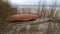 A boat by the sea, gray and cloudy winter day, dune sand and bare bushes