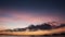 Boat silhouette crossing the ocean at nightfall with orange sky.