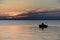 Boat silhouette with the fisherman against the background of a beautiful decline on the bank of the lake