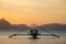 Boat silhouette in the sea on sunset and isles background. Traditional Philippines fishing boat at sunset. Boat in the sea.