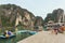 Boat stop with many tourists waiting for traveling inside limestone cave with limestone island in background in summer.