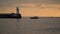 The boat swims past the pier with a lighthouse. evening time